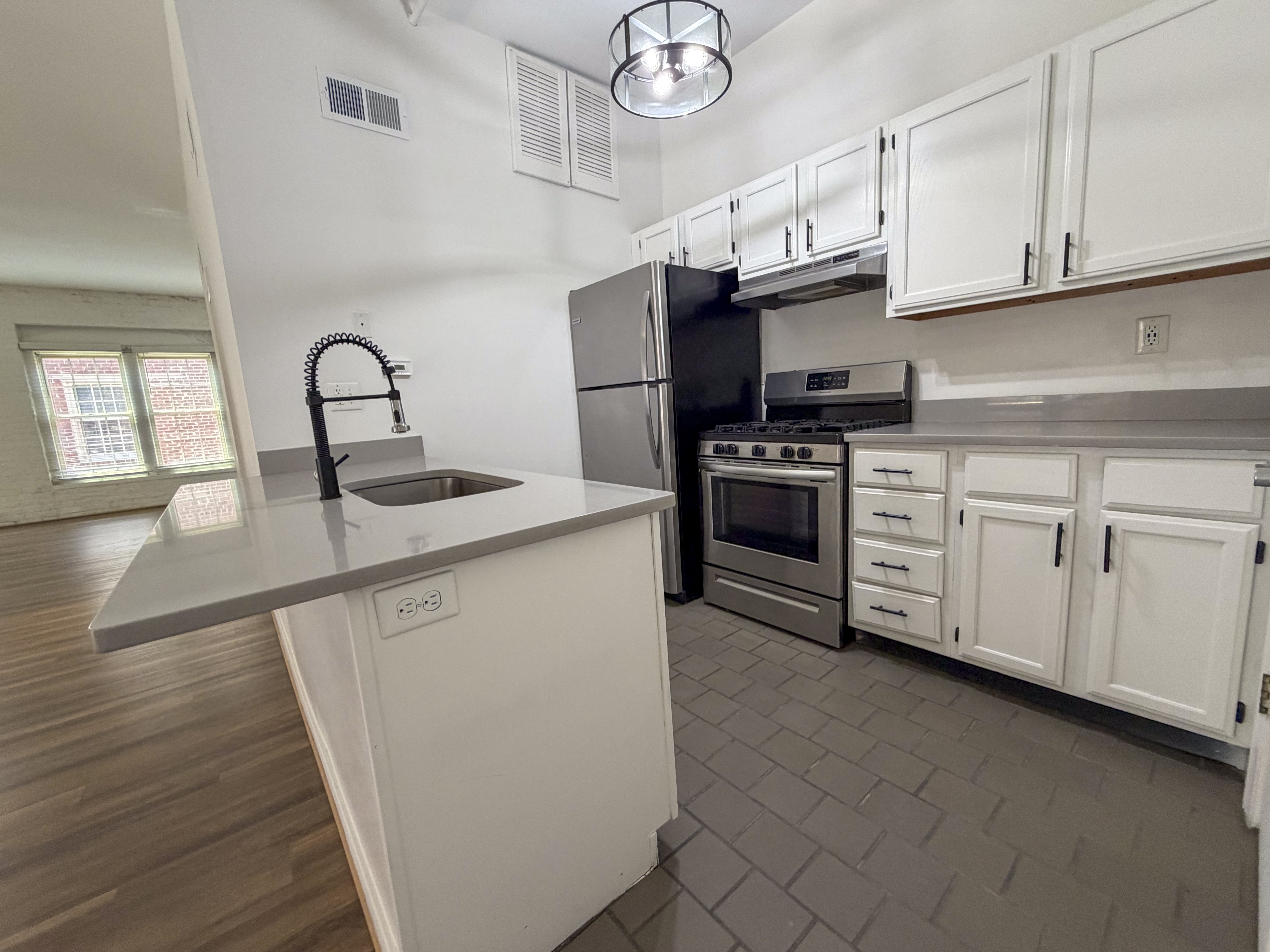 A kitchen with a black refrigerator, stove, and oven.